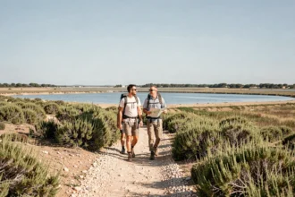 Sentier côtier de la Pointe du Salaison à Mauguio avec couple de randonneurs longeant l'étang de l'Or